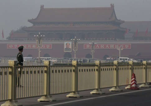 Paramilitary policemen guard and patrol on Tiananmen Square, near Tiananmen Gate, back, where state media says a sports-utility vehicle veered through a crowd and crashed into a stone bridge / AP