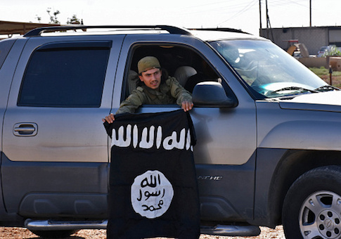 A member of the Syrian pro-government forces holds an Islamic State (IS) group flag after they entered the village of Dibsiafnan on the western outskirts of the Islamist's Syrian bastion of Raqqa