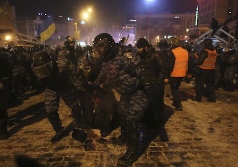 Riot police officers detain a protester in Kiev