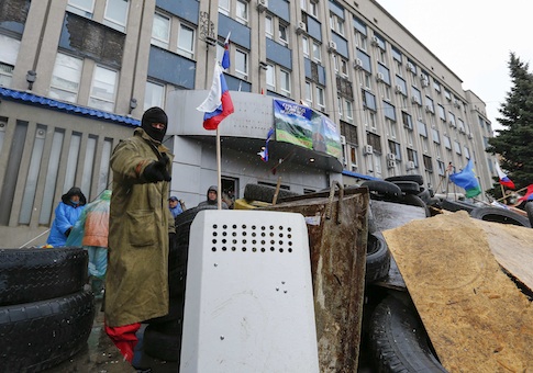 A pro-Russian protester gestures as he stands guard at a barricade in front of the seized office of the SBU state security service in Luhansk