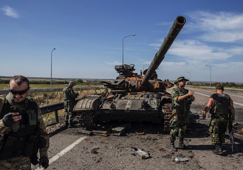 Pro-Russian rebels stand near a burnt-out Ukrainian tank outside the destroyed airport in Luhanks