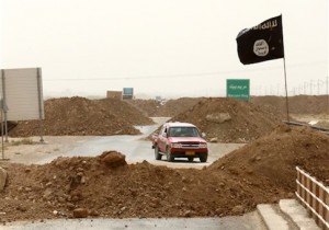 Islamic State militants pass a checkpoint bearing the group's trademark black flag in the village of Maryam Begg in Kirkuk, 290 kilometers (180 miles) north of Baghdad, Iraq