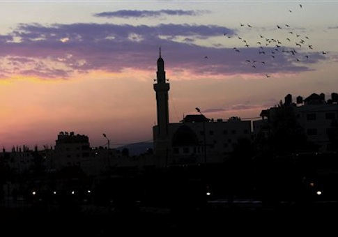 Birds fly over a mosque at the sunrise in the West Bank refugee camp of Jenin early, Thursday, Oct. 2