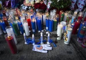 Candles and other items left by visitors make up a growing makeshift memorial Tuesday, Dec. 23, 2014, near the site where New York Police Department officers Rafael Ramos and Wenjian Liu were murdered in the Brooklyn borough of New York