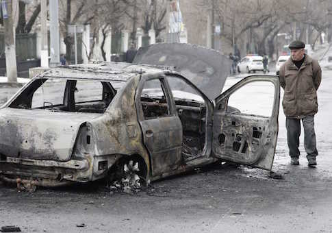 A man looks at a burnt car near a trolleybus stop in Donetsk, January 22, 2015
