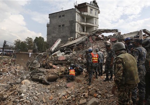 Nepalese policemen look for survivors in the debris of a building that collapsed
