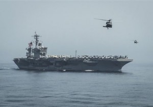 In this April 13, 2015 photo released by U.S. Navy Media Content Services, helicopters fly from the aircraft carrier USS Theodore Roosevelt during a vertical replenishment with the aircraft carrier USS Carl Vinson in the Gulf of Oman