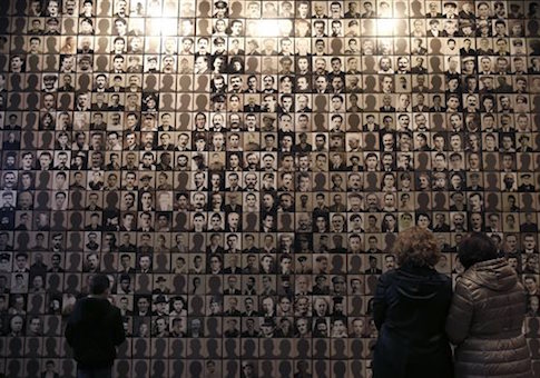 In this photo taken Saturday, March 21, 2015, visitors look at portraits of victims at the Holocaust Museum in the town of Kalavryta, western Greece