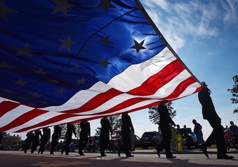 An oversized American Flag is carried during the start of a Veterans Day Parade