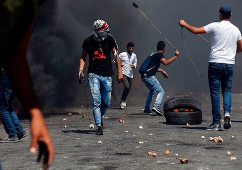 Palestinian protesters throws stones towards Israeli security forces during clashes