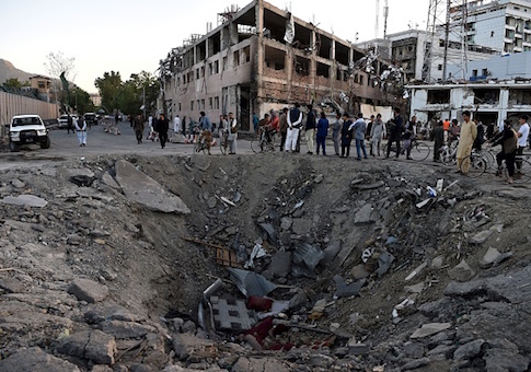 Afghan security forces and residents stand near the crater left by a truck bomb attack in Kabul on May 31