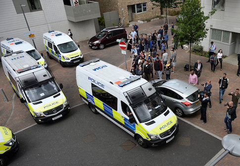 Police vans leave carrying a number of women who were detained after a block of flats was raided in Barking, east London, Britain