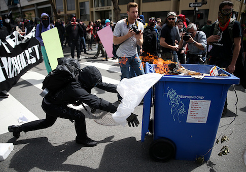 Protesters push a burning recycling bin at Trump supporters during a "Patriots Day" free speech rally on April 15, 2017 in Berkeley, California