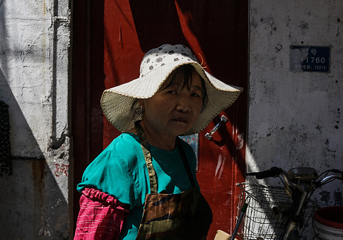 A Chinese construction woman looks on as she walks in the old quarters in Shanghai on September 13, 2017 / Getty Images