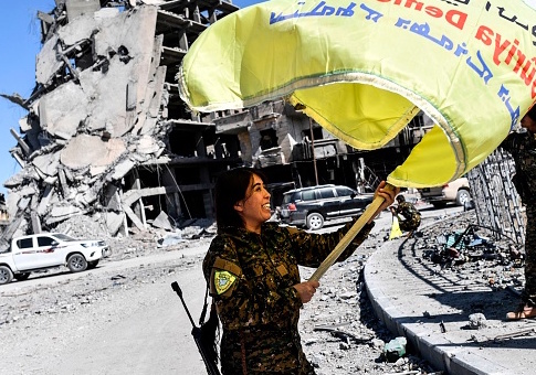 Rojda Felat, a Syrian Democratic Forces (SDF) commander, waves her group's flag at the iconic Al-Naim square in Raqa on October 17, 2017. US-backed forces said they had taken full control of Raqa from the Islamic State group, defeating the last jihadist holdouts in the de facto Syrian capital of their now-shattered "caliphate". / Getty Images