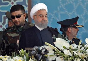 Iranian President Hassan Rouhani sits among senior army staff