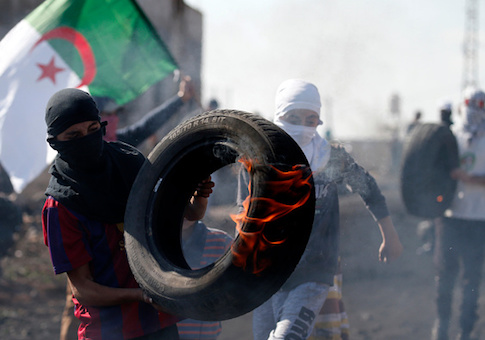 A Palestinian protester carries a burning tire during clashes with Israeli forces