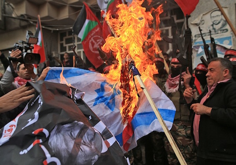 Palestinian protestors burn the Israeli flag and a poster of President Donald Trump