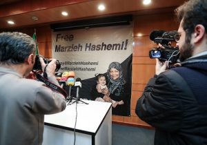 Journalists photograph and film a poster depicting U.S. born Iranian journalist Marzieh Hashemi